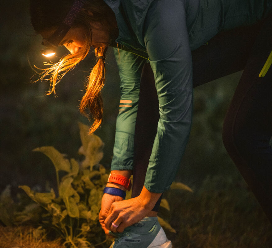 Woman using warm light headlamp to tie her shoes